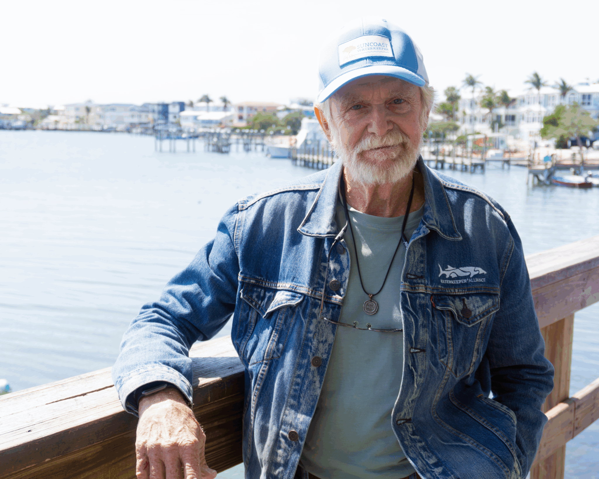 A man leans on a railing by the water