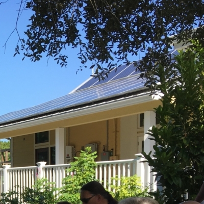 Outsite of the Florida House Institute. Yellow house with soar panels and side porch