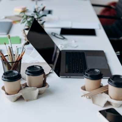 Computer, pens, paper, coffee, phone, and notebook sitting on a white desk